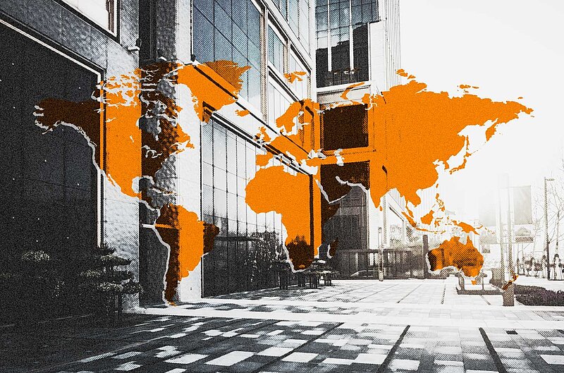 Weltkarte in Orange vor einem Bürogebäude